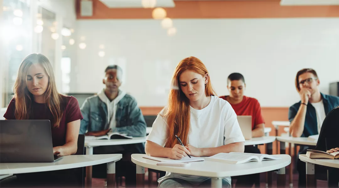 Kuusi opiskelijaa istuu pulpettiensa takana