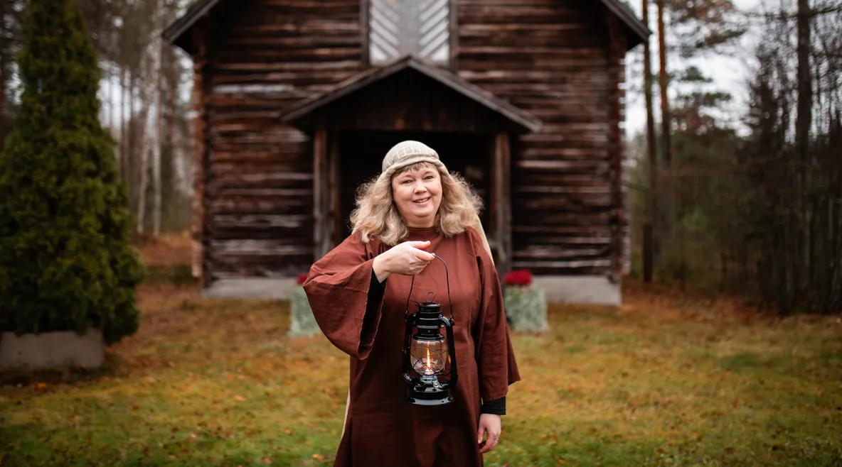 Johanna Talo öljylamppu kädessä riihen edessä.