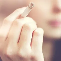 Nuori nainen tupakka kädessä. 