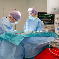 Kirurgi ja sairaanhoitaja leikkaussalissa potilaan äärellä. 