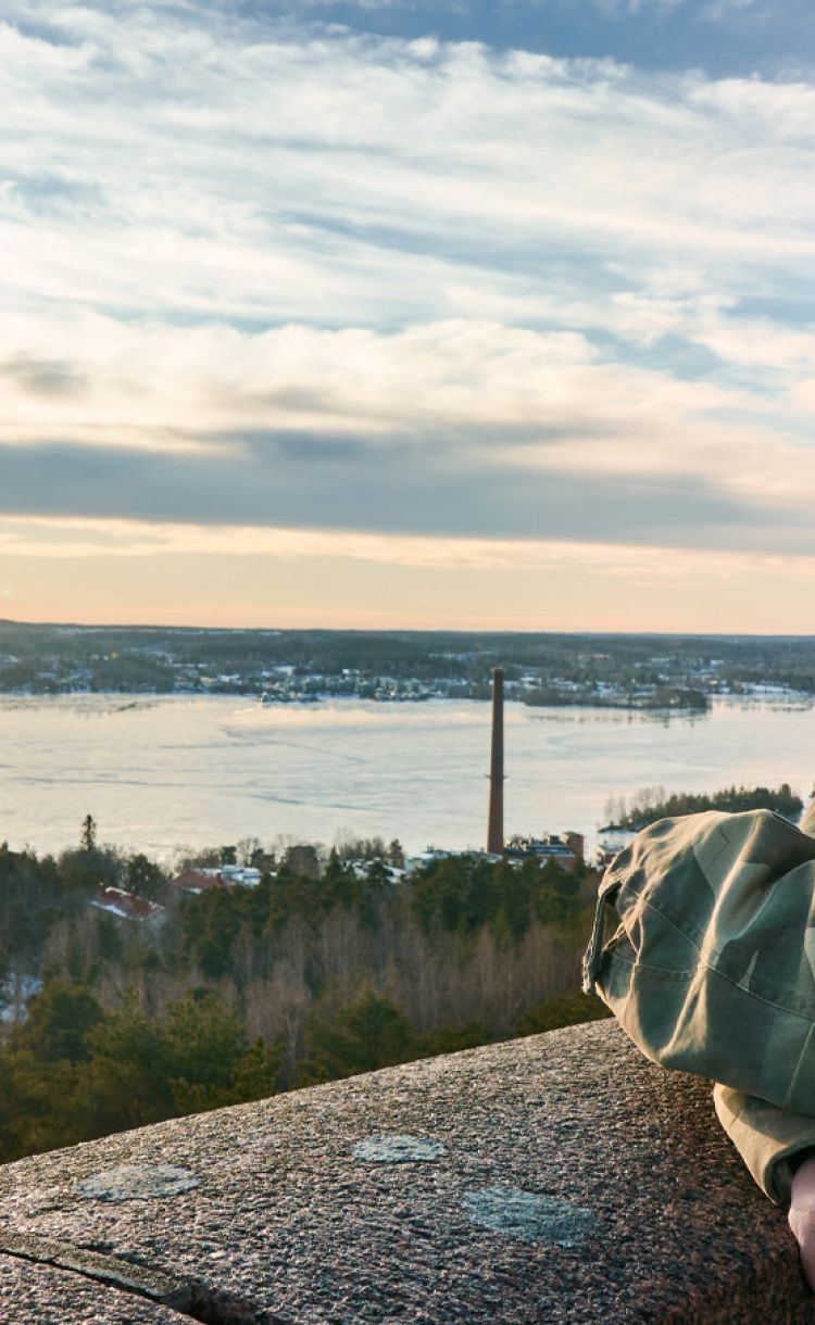 Mielenterveyshoitaja Vesa Suonsyrjä nojailee betoniseen kaiteeseen kaunis merimaisema taustalla.