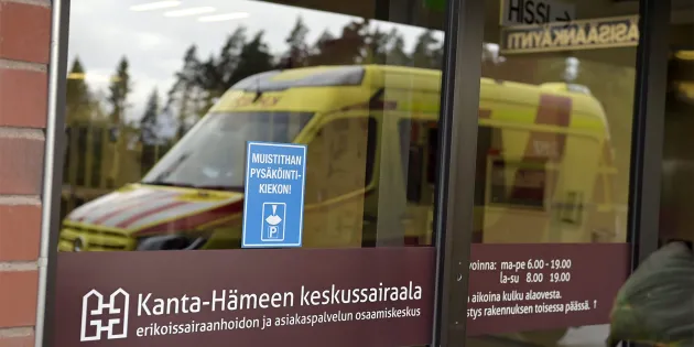 Ambulanssin kuva heijastuu Kanta-Hämeen keskussairaalan lasiovista.