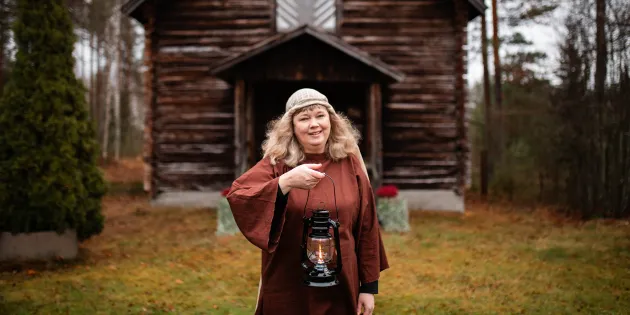 Johanna Talo öljylamppu kädessä riihen edessä.