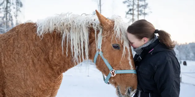 Terveydenhoitaja Nina Salonen halaa Peppi-hevosta.