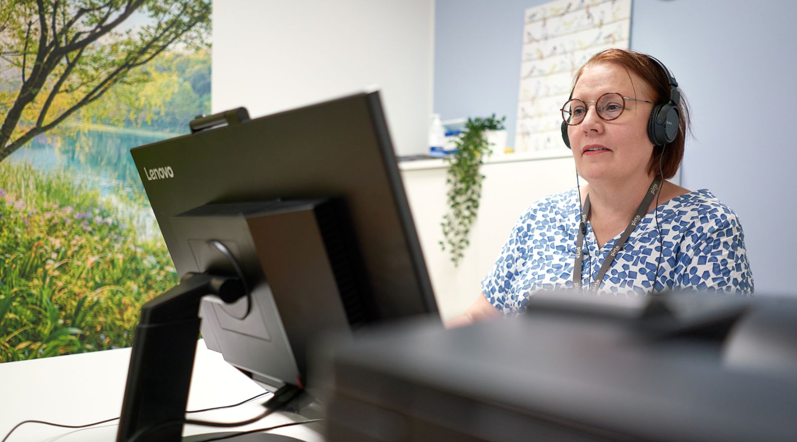 Työterveyshoitaja Kirsti Pennanen työpaikallaan tietokoneen ääressä.